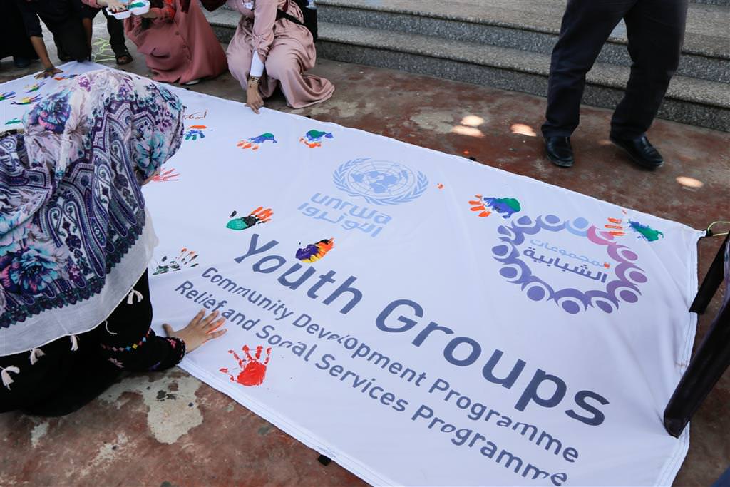 عدد من الشباب يطبعون بأيديهم في اليوم العالمي للشباب في نهاية اليوم المفتوح الذي عقده برنامج الإغاثة والخدمات الاجتماعية في شارم بارك في غزة.