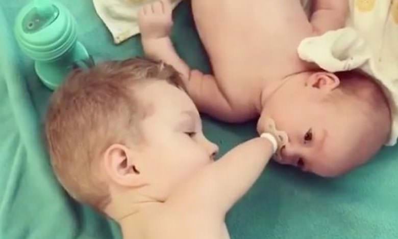 فيديو يأسر القلب.. طفل فاقد لذراعيه يساعد أخاه الرضيع