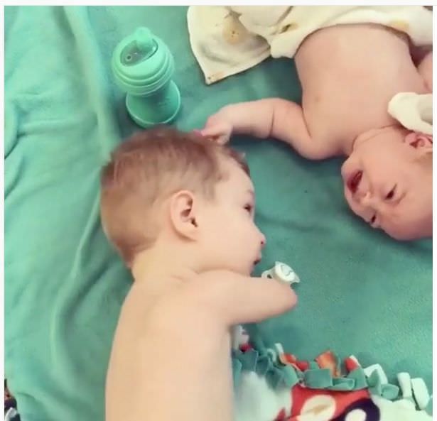 فيديو يأسر القلب.. طفل فاقد لذراعيه يساعد أخاه الرضيع