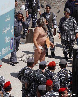 رجل شبه عارٍ أمام السراي مع يافطة انا لبناني أنا حمار
